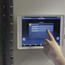 Hand pressing iPad to control the motorized window treatments.