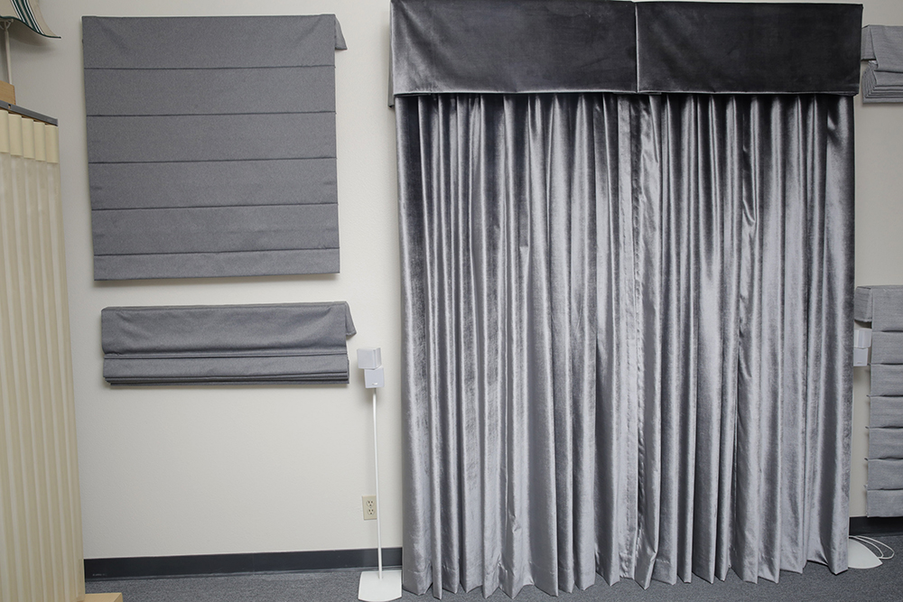 Gray automated drapery with top treatment placed in front of a TV and used as a home theater curtain