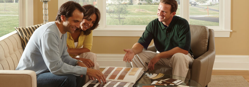 A design consultant shows a couple a sample book with many fabric colors to choose from.