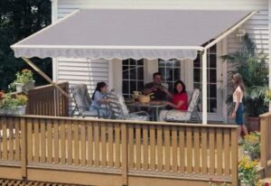 Grey motorized awning covering a family sitting on a deck