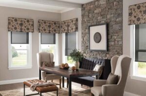 Living room with stone accent wall, cream colored walls, and windows with patterned valances