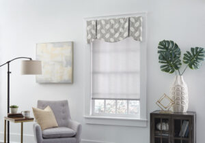 Light roller shade covers a window in living room, topped with patterned grey and white fabric pleated valance