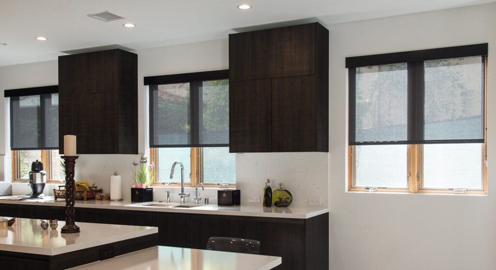 image shows black solar shades covering three windows in a modern styled kitchen